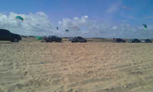 La caravana de camionetas estacionada en la playa mientras sus propietarios practicaban kitesurf.