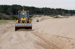 Maquinaria de la Intendencia de Maldonado retirando arena de la Rambla Costanera de Punta Colorada, Playa Brava, consecuencia de las sudestadas que naturalmente desplazan las dunas del lugar.